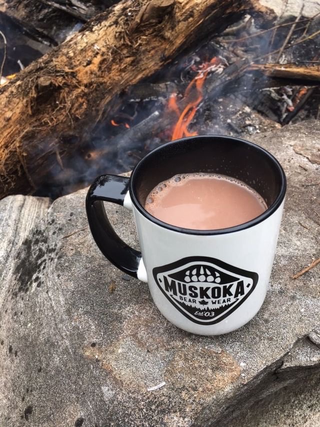 Muskoka Bear Wear coffee cup beside the fire