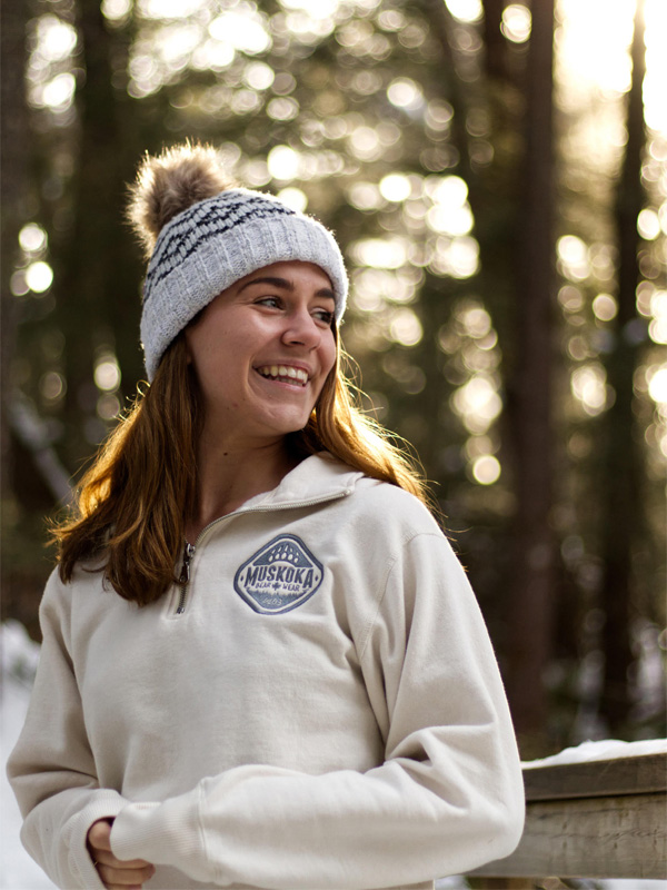 Canadian woman looking off to the side, standing in a forest, wearing a knit toque and Muskoka Bear Wear Ladies Quarter Zip