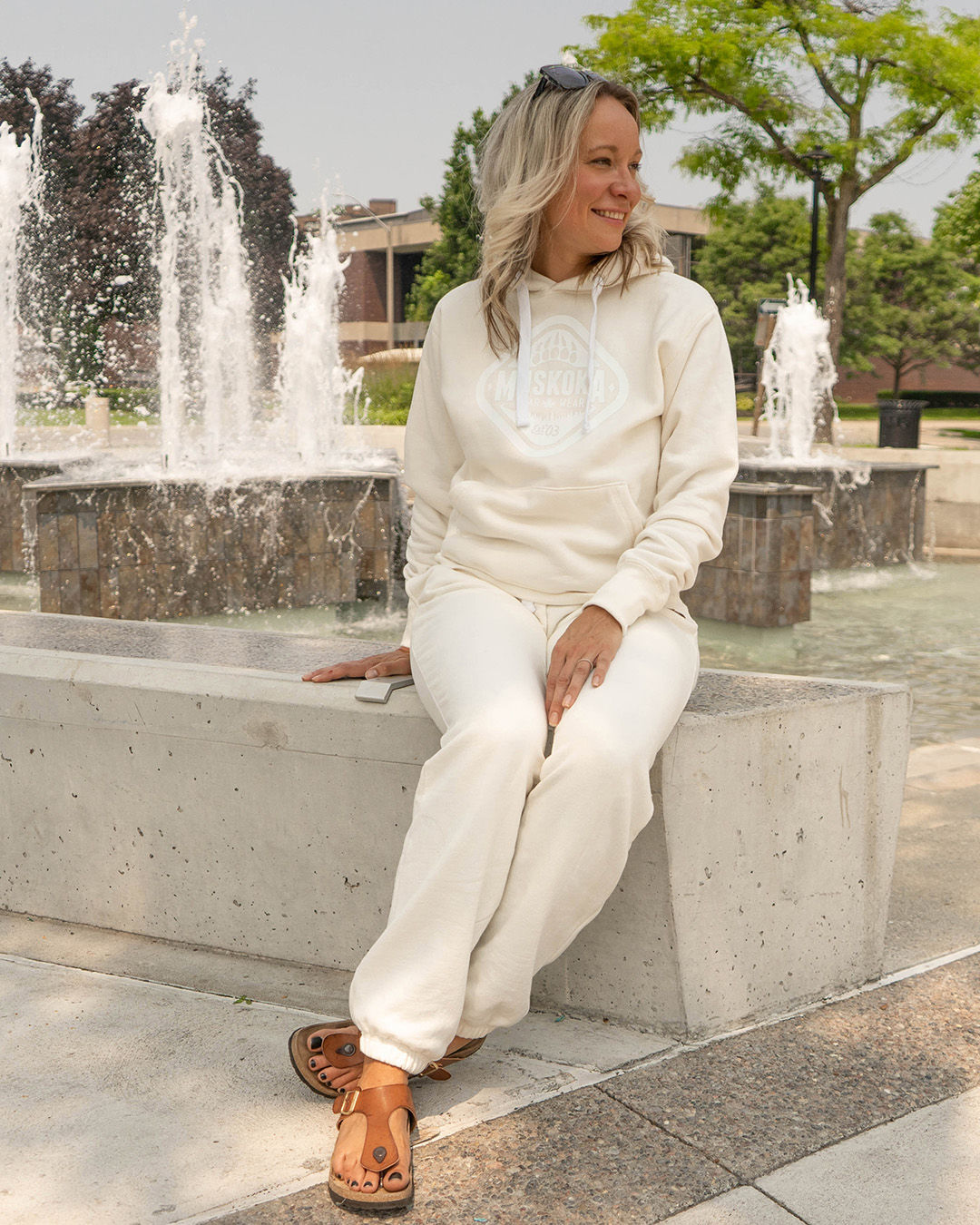 Canadian Woman sitting in front of fountain in Galt, Ontario wearing a matching Ivory sweater and sweatpants outfit
